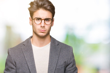 Young business man wearing glasses over isolated background skeptic and nervous, frowning upset...