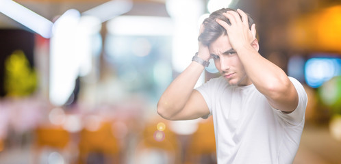 Young handsome man wearing white t-shirt over isolated background suffering from headache desperate and stressed because pain and migraine. Hands on head.