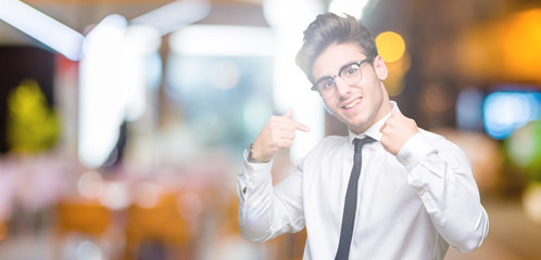 Young business man wearing glasses over isolated background looking confident with smile on face,...