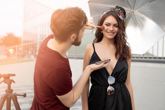 Man Makeup Artist / Stylist Putting On Makeup On Pretty Girl Fashion Model 