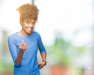 Beautiful young african american woman over isolated background Beckoning come here gesture with hand inviting happy and smiling