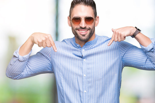 Young handsome man wearing sunglasses over isolated background looking confident with smile on face, pointing oneself with fingers proud and happy.