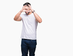 Fototapeta premium Handsome man wearing white t-shirt over white isolated background Doing heart shape with hand and fingers smiling looking through sign