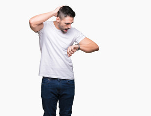 Handsome man wearing white t-shirt over white isolated background Looking at the watch time worried, afraid of getting late