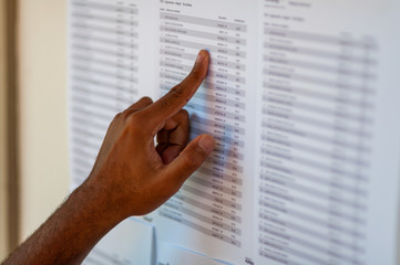 Man's hand pointing to a name list, trying to find some name - obrazy, fototapety, plakaty