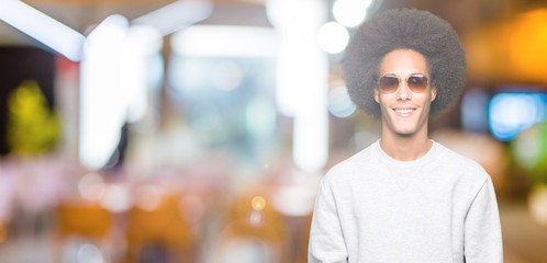 Fototapeta na wymiar Young african american man with afro hair wearing sunglasses with a happy and cool smile on face. Lucky person.