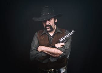 Cowboy standing with crossed arms, holding a revolver handgun.