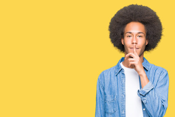 Young african american man with afro hair asking to be quiet with finger on lips. Silence and...