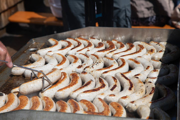 Many grilled bratwurst sizziling on a grill