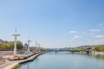 Fototapeta na wymiar Pont de l'Universite bridge in Lyon, France over a panorama of the riverbank of the Rhone river (Quais de Rhone) with older buildings and the university building in background