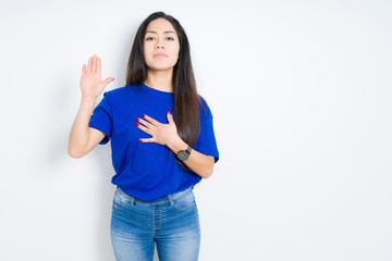 Beautiful brunette woman over isolated background Swearing with hand on chest and open palm, making...