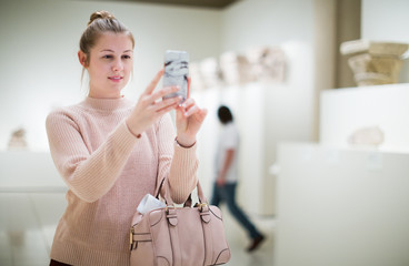 woman using smartphone and standing in art museum