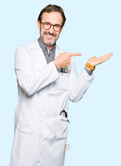 Middle age doctor men wearing medical coat amazed and smiling to the camera while presenting with hand and pointing with finger.