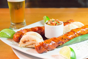 Chorizo acompañado con arepa limón y cerveza