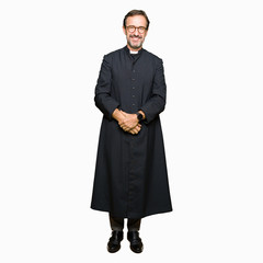 Middle age priest man wearing catholic robe Hands together and fingers crossed smiling relaxed and...