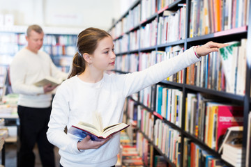 girl searching for textbooks on bookshelves
