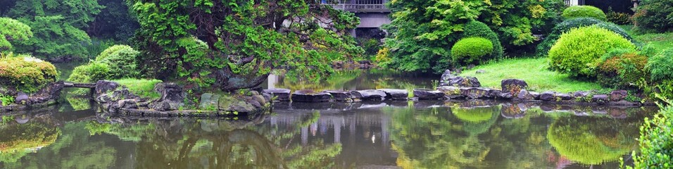 Fototapeta na wymiar Traditional Japanese gardens in public parks in Tokyo, Japan. Views of stone lanterns, lakes, ponds, bonsai and wildlife walking around paths and trails. Asia. 