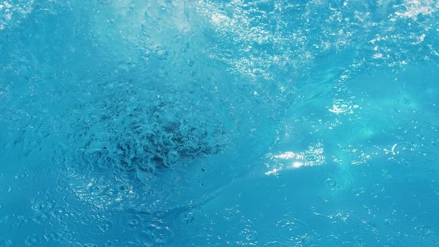 active young woman jumps into the clear blue water of the pool on resort in the hotel in Slow motion