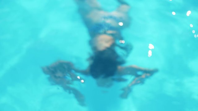 cute young girl emerges from under water in the pool and smiling to the camera in Slow motion