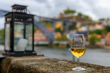 Glass of port wine with the blurred cityscape of Porto Portugal and a lantern in the background