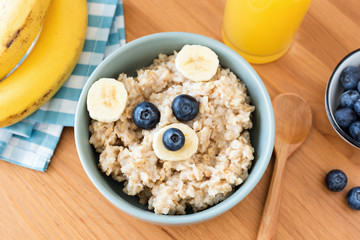 Kids breakfast oatmeal porridge with funny teddy bear face made with fruits on a wooden table, top view