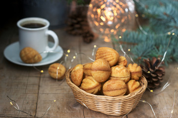 Homemade shortbread cookies in various shapes, filled with caramel on the background of fir branches and garlands.