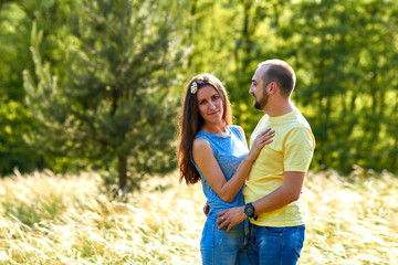 Fototapeta premium Lovers. A young couple. The guy with the girl are walking in the forest. Loving couple hugs sensually. Lovers man and woman in the arms of each other. Romantic walk in the forest. Loving relationship