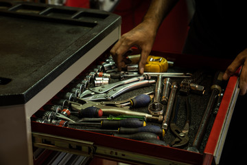 A set of tools for repair in car service - mechanic's hands, close up. Choosing a tools in toolbox for improvement the car or vehicles. Mechanic picking up the tools in the garage or home / workshop