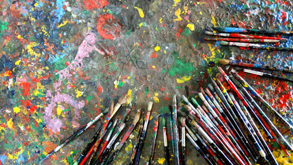 Obraz premium Used paint brushes on a table with pigments stained, arts and handworks concept image.