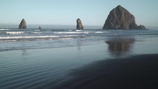 Haystack Rock and Surf Cannon Beach 4K UHD. Sunrise at Haystack Rock and the Needles in Cannon Beach, Oregon as the surf washes up onto the beach. United States.