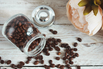 Coffee beans in a glass jar on a light wooden background