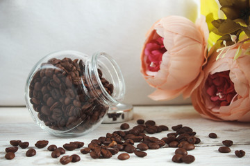 Coffee beans in a glass jar on a light wooden background