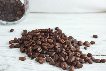 Coffee beans in a glass jar on a light wooden background