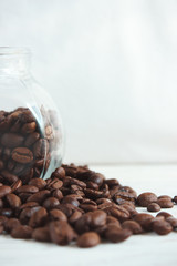 Coffee beans in a glass jar on a light wooden background