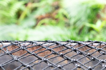 Black mesh used as flooring for placing items And there is a green forest in the background On a clear day. for copy space background.