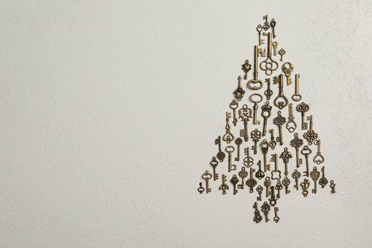 Flat lay composition with Christmas tree made of keys on light background, space for text