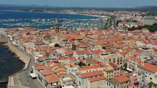 Aerial shot over Alghero old town, cityscape view on a beautiful day with harbor and open sea in view. Alghero, Italy. Panoramic aerial view of Alghero, Sardinia, Italy.