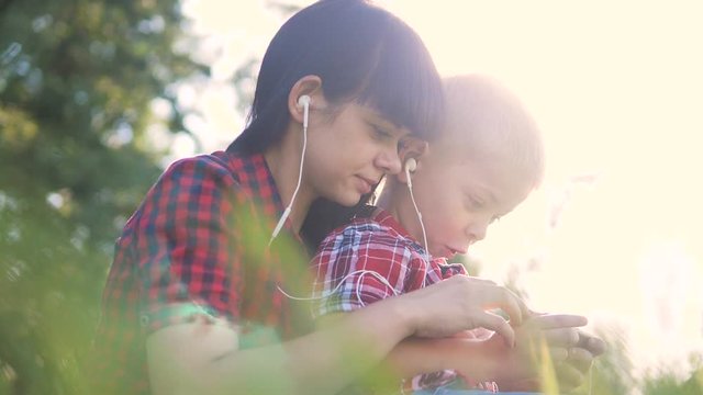 happy family funny video slow motion play music teamwork outdoors. Mom and son lifestyle listen to music on smartphone in the same headphones for two. happy family mother woman and son little boy