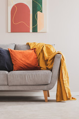 Yellow blanket on grey sofa with orange and black pillows