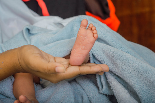 Pies del bebé recién nacido en la palma de su madre. Los pies del niño en la mano de su madre sobre una manta. Nuevo concepto de familia, cuidado y protección del bebé. Acercamiento de pies de bebé