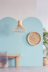 Fototapeta na wymiar Wicker chandelier above wooden bench in simple natural blue interior