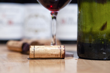 Closeup glass of red wine on background of bottles, corks. Concept wine Burgundy, Tuscany,...