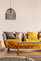 Copy space on empty white wall of fashionable living room interior with yellow and orange accents