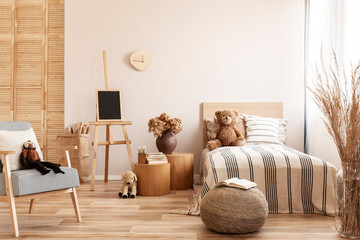 Teddy bear on single wooden bed in natural kid's bedroom
