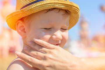 Mother puts cream on her son's face. Caring for baby skin. Sunscreens in the travel