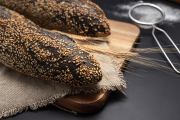 Homemade sourdough bread baguette on vintage towel on black background. Food. Culinary.