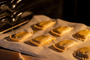 Empanadillas , small filling tuna pies in roasting tray  in oven. Cooking process background. Natural atmosphere lifestyle image.