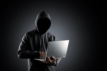 Cybercrime, hacking and technology crime. no face hacker with laptop on black background with...
