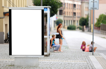 Fototapeta Bilbord reklamowy w centrum miasta, w tle dzieci na chodniku, przystanku autobusowym.  obraz