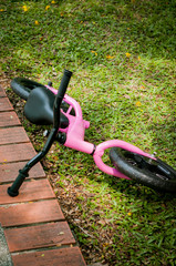 Fototapeta na wymiar Pink bike for little girl. A pink bike parking in the park near the pavement.